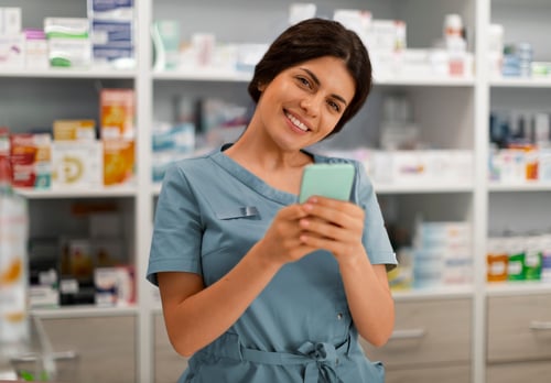 farmacéutica utilizando el celular y sonriendo